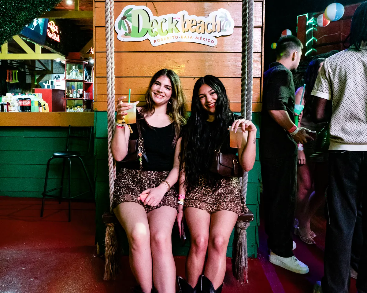 Amigas en el columpio bajo el letrero de Deck on the beach, Rosarito